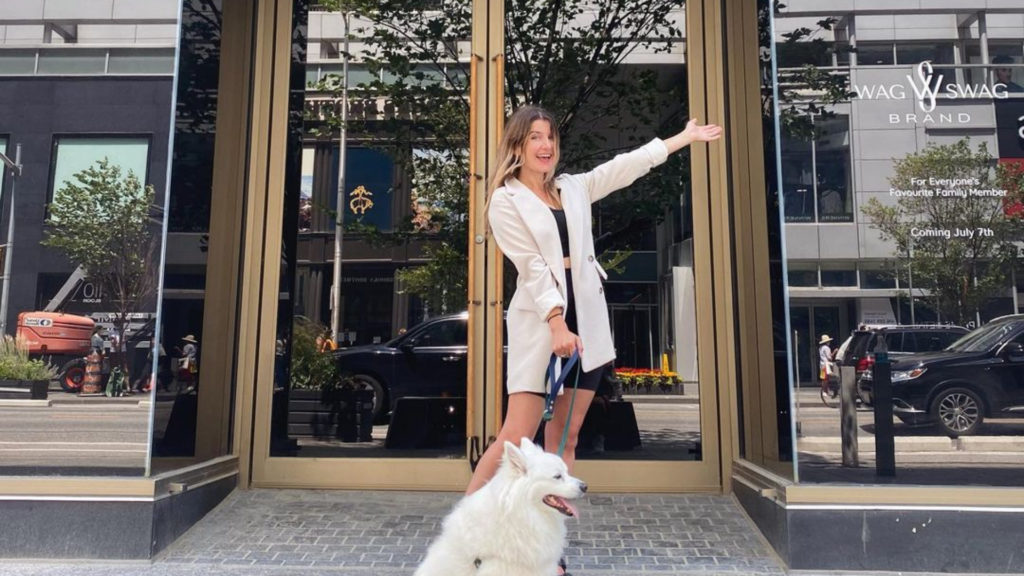 A photo of a person posed with their dog in front of the Wag Sawg boutique storefront on Bloor.